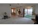 Living room featuring neutral carpeting, a mirrored wall, and views of the kitchen and screened in porch at 1077 Willow Wood Dr, Port Orange, FL 32129