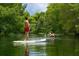 A Personal paddleboards on a serene river surrounded by lush greenery. Kayaker in the background at 11222 Rapallo Ln, Windermere, FL 34786