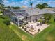 Aerial view showcasing a brick patio with a fire pit, screened-in lanai, and lush landscaping in the backyard at 1156 Rivercrest Ct, Port Orange, FL 32128
