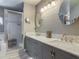 Bright bathroom featuring double vanity, marble countertop, round mirrors, and a modern shower at 1156 Rivercrest Ct, Port Orange, FL 32128