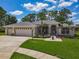 Charming single-story home with a three-car garage, lush lawn, and tropical landscaping at 1156 Rivercrest Ct, Port Orange, FL 32128