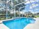 Refreshing pool with a screened enclosure, waterfall feature, and blue lounge chairs nearby at 1156 Rivercrest Ct, Port Orange, FL 32128