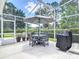 Screened-in pool area with outdoor dining set, grill, and lush landscaping for privacy at 1156 Rivercrest Ct, Port Orange, FL 32128