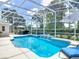Sparkling pool with waterfall feature, surrounded by a screened enclosure and tropical landscaping at 1156 Rivercrest Ct, Port Orange, FL 32128