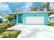 Lovely light blue home featuring an attached garage, manicured landscaping, and a bright and inviting facade at 1209 Palmetto St, New Smyrna Beach, FL 32168