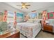 Comfortable bedroom with a floral-patterned quilt, large windows, and beach-themed decor at 13 Essex Dr, Ormond Beach, FL 32176