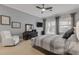This bedroom features a ceiling fan, a TV, a white leather recliner and neutral gray and beige decor at 133 Via Capri, New Smyrna Beach, FL 32169