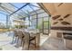 Covered outdoor kitchen with built-in grill and counter, under a screened enclosure, with a canal view at 133 Via Capri, New Smyrna Beach, FL 32169