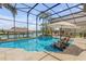 Exterior view of a screened-in pool with seating in the pool, a waterfall feature, and view of the waterfront at 133 Via Capri, New Smyrna Beach, FL 32169