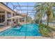 Screened pool with seating in the pool, a waterfall feature, and access to the waterfront on a sunny day at 133 Via Capri, New Smyrna Beach, FL 32169