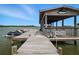 Private boat dock featuring a covered slip, boat lift, and wooden walkway at 1601 S Riverside Dr, Edgewater, FL 32132