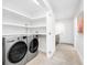 Bright laundry room with stainless steel appliances, white cabinets, and tile flooring with access to the backyard at 1601 S Riverside Dr, Edgewater, FL 32132