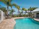 Backyard pool with a lounge chair on a brick patio with palm trees and waterfront view at 1601 S Riverside Dr, Edgewater, FL 32132