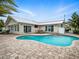 An inviting pool with a brick patio is nestled alongside a charming white brick home at 1601 S Riverside Dr, Edgewater, FL 32132