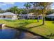 Well-manicured lawn leading to a serene pond with a home featuring a screened-in pool at 1688 Town Park Dr, Port Orange, FL 32129