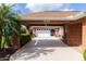Carport with brick columns leading to a garage and entryway with mature landscaping at 1688 Town Park Dr, Port Orange, FL 32129