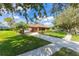 A well-kept single-story brick home with mature trees, lush landscaping, and a long driveway at 1688 Town Park Dr, Port Orange, FL 32129