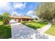 Charming single-story brick home with a long driveway, lush landscaping, and mature trees at 1688 Town Park Dr, Port Orange, FL 32129