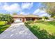 Charming single-story brick home with a well-manicured lawn, mature landscaping, and a long driveway at 1688 Town Park Dr, Port Orange, FL 32129
