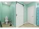 Modern bathroom with a white barn door, turquoise walls, and a toilet at 1748 Savannah Ln, Port Orange, FL 32128
