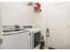 Well-lit laundry room featuring a modern washer and dryer set with storage shelf and door at 1748 Savannah Ln, Port Orange, FL 32128