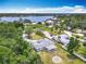 Expansive aerial view of a single story home next to a lake surrounded by lush greenery and an inviting neighborhood at 1812 Bayview Dr, New Smyrna Beach, FL 32168