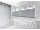 All-white bathroom featuring a large soaking tub with marble surround, tile floor, and mirrored closet at 1812 Bayview Dr, New Smyrna Beach, FL 32168