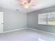 This bedroom has tile floors, a ceiling fan, and a window overlooking the backyard at 1812 Bayview Dr, New Smyrna Beach, FL 32168