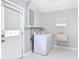Bright laundry room with washer, dryer, utility sink, and tile flooring, with exterior access door at 1812 Bayview Dr, New Smyrna Beach, FL 32168