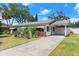 Charming single-story home with well-maintained lawn, carport, and mature trees under a bright blue sky at 1851 Needle Palm Dr, Edgewater, FL 32141