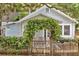 Charming single-story home with a picket fence featuring a vine-covered archway, creating a welcoming entrance at 209 Esther St, New Smyrna Beach, FL 32169