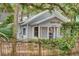 View of a quaint one-story home with a metal roof and light gray paint, complemented by a charming wooden fence at 209 Esther St, New Smyrna Beach, FL 32169
