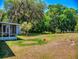 Expansive backyard featuring mature trees, including one draped with Spanish moss, and a screened-in porch for outdoor relaxation at 242 Cypress Ave, Oak Hill, FL 32759