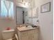 Bathroom with a sink, mirror, and white cabinets beneath a window with sheer curtains at 242 Cypress Ave, Oak Hill, FL 32759
