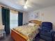Cozy bedroom features a floral-patterned bed, a ceiling fan, and green curtains, creating a peaceful retreat at 242 Cypress Ave, Oak Hill, FL 32759