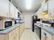 Kitchen features white cabinets, tile floors, and appliances at 242 Cypress Ave, Oak Hill, FL 32759