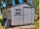 Outdoor shed with gray siding, single door, and window provides extra storage space on the property at 242 Cypress Ave, Oak Hill, FL 32759
