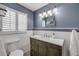 Bathroom featuring a wood vanity, updated lighting, blue accent wall and shuttered window at 2548 E Compton St, Orlando, FL 32806