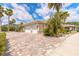Charming home featuring a paver driveway, three-car garage, and lush tropical landscaping at 2913 Linari Ct, New Smyrna Beach, FL 32168