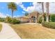 Stunning home exterior with stone accents, arched entryway, lush landscaping, and mature palm trees at 2913 Linari Ct, New Smyrna Beach, FL 32168