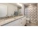 Bright bathroom features double sinks with granite countertops and shower with patterned curtain at 3136 Portofino Blvd, New Smyrna Beach, FL 32168
