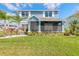 Charming blue two-story home with a screened-in porch, lush landscaping, and a well-manicured lawn at 3136 Portofino Blvd, New Smyrna Beach, FL 32168