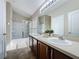 This bathroom features double sinks, wood cabinets, an over-sink light and a shower with glass door at 3311 Pine Oak Trl, Sanford, FL 32773