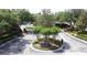 Aerial view of a community entrance boasting a circular median with verdant plants, and brick fencing at 3311 Pine Oak Trl, Sanford, FL 32773