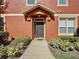 Front exterior view of a townhome featuring manicured landscaping, a covered entry and a dark colored front door at 3311 Pine Oak Trl, Sanford, FL 32773