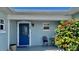 Front porch with a bright blue door, adorned with a decorative chair and lush foliage at 34 Richmond Dr, New Smyrna Beach, FL 32169