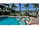 Screened-in pool and spa featuring brick-paver decking with waterfront views and mature palm trees at 34 Richmond Dr, New Smyrna Beach, FL 32169