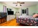 Comfortable bedroom featuring wood floors, updated ceiling fan, television and dresser at 35 Knollwood Estates Dr, Ormond Beach, FL 32174