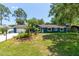 Charming blue home features a manicured lawn, tropical landscaping, and a welcoming entrance at 35 Knollwood Estates Dr, Ormond Beach, FL 32174