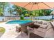 Outdoor patio seating area with an umbrella for shade and palm trees in the background at 35 Knollwood Estates Dr, Ormond Beach, FL 32174